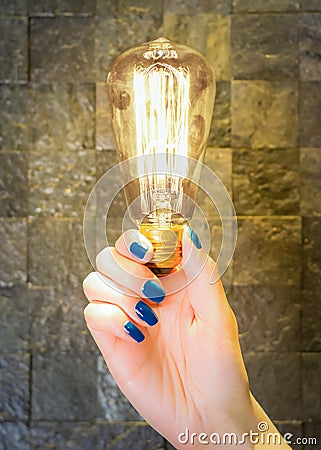 Excellent idea concept, female hand holding classic lit lamp Stock Photo