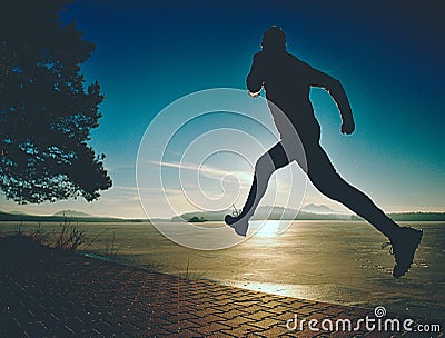 Excercising silhouette against morning sun at bay shore Stock Photo