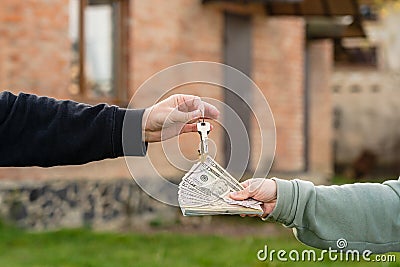 Exchange cash and key home in front of home. Buying or renting real estate. Mortgage. Insurance Stock Photo