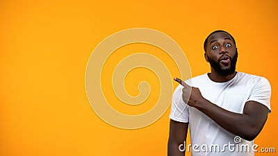 Excited African-American man pointing finger into background, template for text Stock Photo