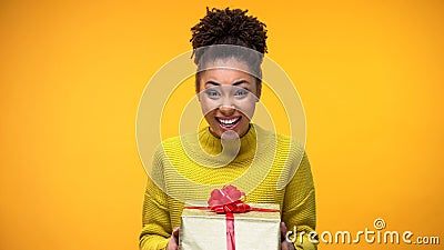 Excited African-American woman holding gift box, pleasant birthday surprise Stock Photo