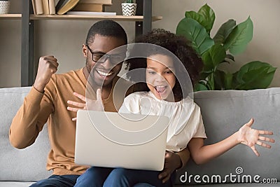 Excited african father and kid girl winners looking at laptop Stock Photo