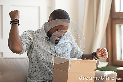 Excited african man customer receive open parcel box at home Stock Photo