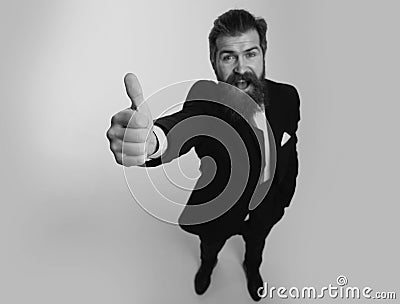 Excited amazed business man in black suit smiling and showing thumbs up. Escape from crisis. Funny face. Great Idea Stock Photo