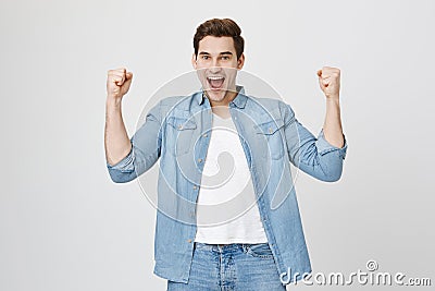 Excited and amazed young european man raising fists, expressing happiness and victory. Football player cheers for his Stock Photo