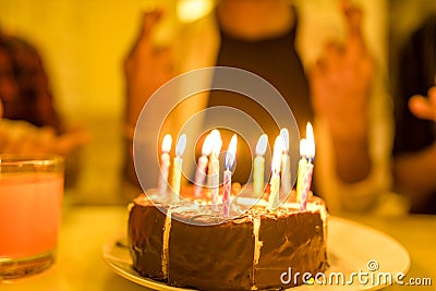 Excited arabian man ready to blow out candles on cake on birthday party with happy friends in the house Stock Photo