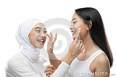 excited asian bestfriend applying face cream with finger hands Stock Photo