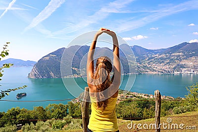 Excited attractive young woman in sportswear stretching enjoying Lake Iseo landscape in the morning, North Italy. Cheerful mood Stock Photo