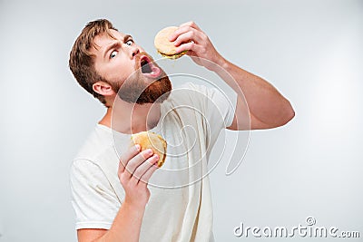 Excited bearded man greedily eating hamburgers Stock Photo