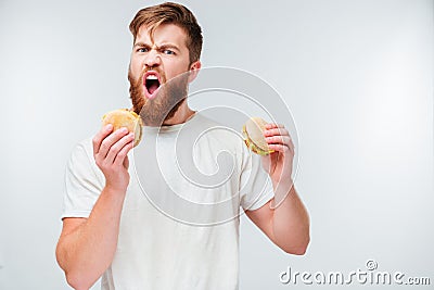 Excited bearded man greedily eating hamburgers Stock Photo