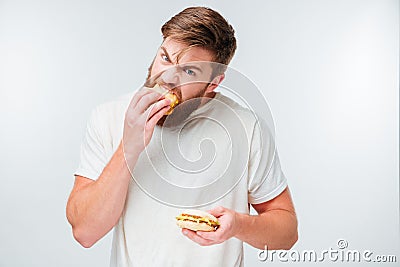 Excited bearded man greedily eating hamburgers Stock Photo