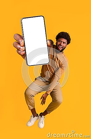 Excited black guy holding smartphone, jumping up Stock Photo