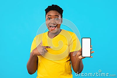 Excited Black Woman Pointing At Phone Screen Over Blue Background Stock Photo