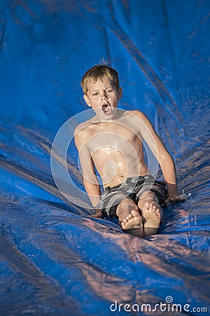 Excited boy playing on a slip and slip outdoors Stock Photo