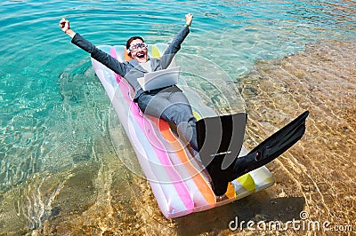 Excited businesswoman floating on lilo with laptop Stock Photo