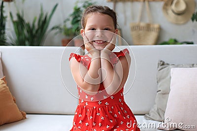 Excited child looking at camera while sitting in living room at home Stock Photo
