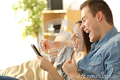 Excited couple checking content in a phone Stock Photo