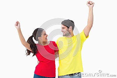 Excited couple cheering in red and yellow tshirts Stock Photo