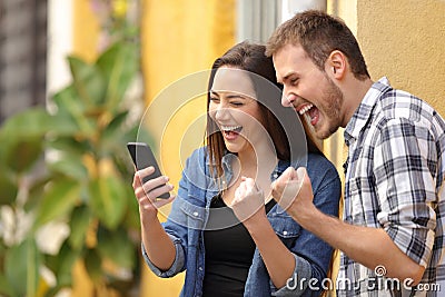 Excited couple finding online offers on phone in the street Stock Photo