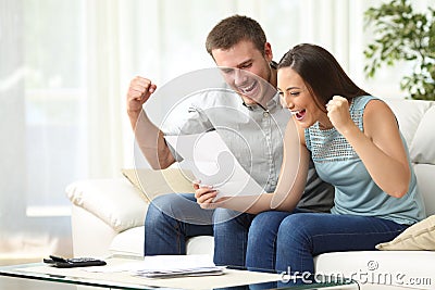 Excited couple reading a letter at home Stock Photo