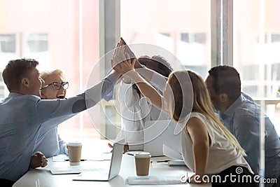 Excited diverse colleagues give high five at meeting Stock Photo