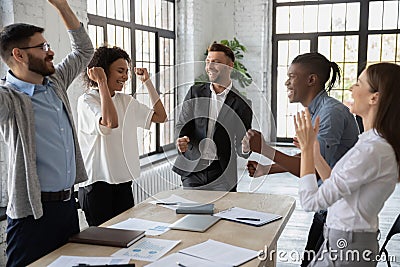 Excited diverse employees celebrating great teamwork result at meeting Stock Photo