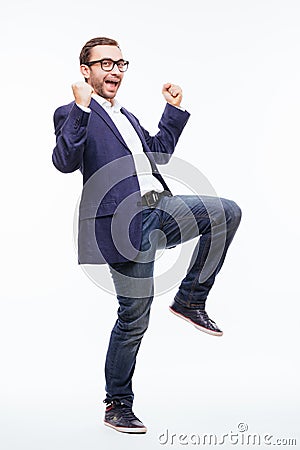 Excited elated happy young business man with beard in classic suit jumping and shouting over white background Stock Photo