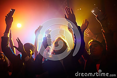 Excited fans waving gadgets with flashlights turned on Stock Photo