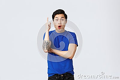 Excited handsome asian man have idea, guy in blue t-shirt raising index finger eureka sign, saying suggestion, made-up Stock Photo