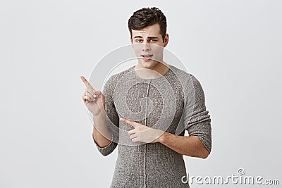 Excited handsome guy indicates with fore finger at copy space for advertisment or promotional text. Amazed attractive Stock Photo