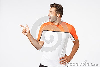 Excited, happy amused masculine sportsman in activewear, attend gym, pointing turning left astonished, gasping from Stock Photo