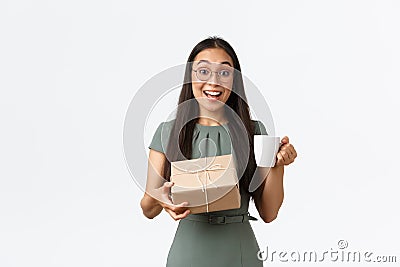 Excited happy asian woman drinking coffee and receive home delivery, holding box package with cheerful smile, finally Stock Photo