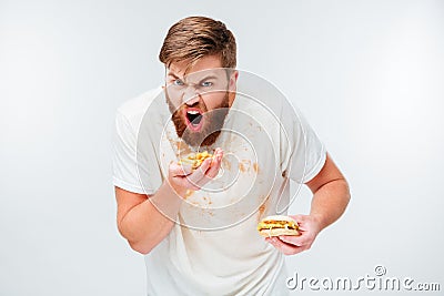 Excited hungry bearded man greedily eating hamburgers Stock Photo