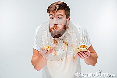 Excited hungry bearded man greedily eating hamburgers Stock Photo