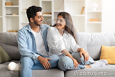 Excited Indian spouses laughing and relaxing on a sofa Stock Photo