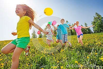 Excited kids with balloons run in field Stock Photo