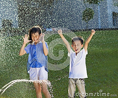 Excited kids has fun playing in water fountain Stock Photo