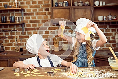 Excited kids playing with dough for shaped cookies Stock Photo