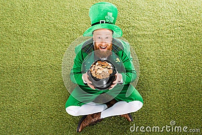 Excited leprechaun with pot of gold sitting Stock Photo