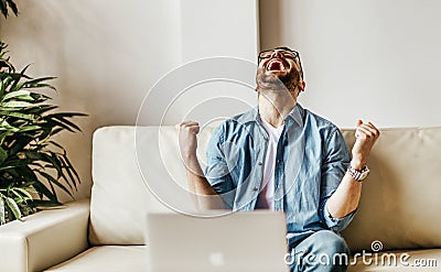 Excited male businessman celebrating victory, success, triumph while working at laptop Stock Photo