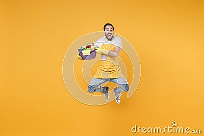 Excited man househusband in apron gloves hold basin detergent bottles washing cleansers doing housework isolated on Stock Photo