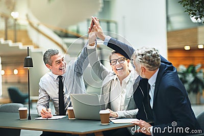 Excited mature businesspeople high fiving together in a modern o Stock Photo