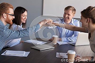 Excited workers join hands engaged in teambuilding activity Stock Photo