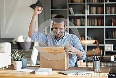 Overjoyed male buyer unbox internet order at home Stock Photo