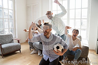 Excited multi-ethnic friends celebrating football victory indoors Stock Photo