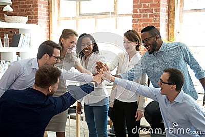 Excited diverse workers join hands at teambuilding activity Stock Photo