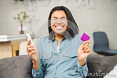 Excited multiracial female bank customer using phone to make easy secure payments online in convenient app. Glad mixed Stock Photo