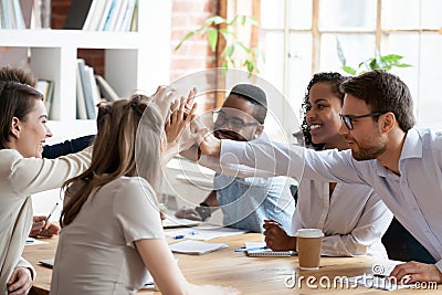 Excited multiracial team giving high five at company meeting Stock Photo