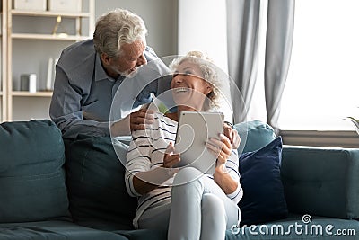 Excited older man and woman having fun with computer tablet Stock Photo