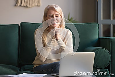 Excited older woman feeling winner sit in front of laptop Stock Photo